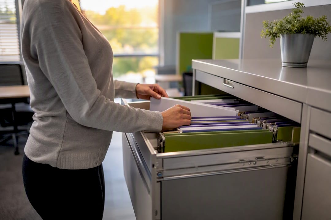 Hands organizing HR folders in filing cabinet